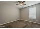 Bedroom with neutral walls, carpeted floor, ceiling fan, and a window for natural light in a cozy space at 18766 N Salerno Dr, Maricopa, AZ 85138