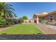 Landscaped backyard features artificial grass, covered patio, and a mature palm tree at 19318 E Reins Rd, Queen Creek, AZ 85142