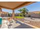 Inviting covered patio with chairs overlooking a landscaped backyard and a fire pit at 19318 E Reins Rd, Queen Creek, AZ 85142