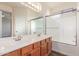 Well-lit bathroom featuring double sinks, wood cabinets, and a glass shower door at 19318 E Reins Rd, Queen Creek, AZ 85142
