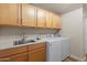 Laundry room with wooden cabinets, stainless steel sink, and modern washer and dryer units at 19700 N 76Th St # 1038, Scottsdale, AZ 85255