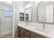 Bathroom featuring double sinks, quartz countertops, wood cabinets, and a glass shower at 20226 N Madison Dr, Maricopa, AZ 85138