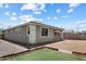 View of the home's gray stucco exterior with covered patio and a small strip of artificial grass in the backyard at 2410 S 124Th Dr, Avondale, AZ 85323
