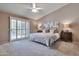 Carpeted main bedroom with a ceiling fan, sliding glass doors, and bedside tables with lamps at 2984 N 152Nd Dr, Goodyear, AZ 85395