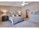 Carpeted main bedroom with a ceiling fan, bedside tables with lamps, and an ensuite bathroom at 2984 N 152Nd Dr, Goodyear, AZ 85395