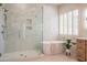 Modern bathroom featuring a glass shower, soaking tub, and marble tiling for a clean, luxurious feel at 3153 E Sierra Vista Dr, Phoenix, AZ 85016