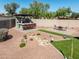 Backyard showcasing a covered outdoor kitchen, fire pit, and manicured desert landscaping at 41793 W Canasta Ln, Maricopa, AZ 85138