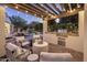 Outdoor kitchen and patio area with grill, fireplace, seating, and string lights overlooking a pool and lush greenery at 4350 S White Dr, Chandler, AZ 85249