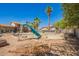 View of an in-ground pool with a slide in a backyard with desert landscaping and palm trees at 7259 E Glencove St, Mesa, AZ 85207