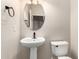 Small half bathroom with oval mirror, pedestal sink, and toilet at 10830 W El Cortez Pl, Peoria, AZ 85383