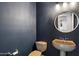 Elegant half bathroom featuring a round mirror and pedestal sink against a blue accent wall at 11866 N 143Rd Ave, Surprise, AZ 85379