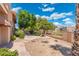 Landscaped backyard with a decorative fountain, a fire pit, and mature trees at 1338 E Greenway Cir, Mesa, AZ 85203