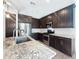 Bright kitchen with stainless steel appliances, granite countertops, tiled backsplash, and dark wood cabinets at 24776 N 171St Ln, Surprise, AZ 85387