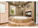 Relaxing bathroom showcasing a garden tub, a fireplace, beautiful tile work, and neutral accents at 2558 E Page Ct, Gilbert, AZ 85234