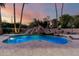 Inviting pool with rock waterfall feature, surrounded by lush landscaping, and a serene sunset backdrop at 2558 E Page Ct, Gilbert, AZ 85234