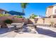This backyard has a stone firepit, a table with chairs, and shade from umbrellas at 25818 N 68Th Ave, Peoria, AZ 85383