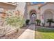 Inviting front entrance showcases a walkway leading to a charming arched doorway, lush greenery, and desert landscaping at 2642 S Joplin --, Mesa, AZ 85209