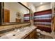 Well-lit bathroom featuring a single sink, large mirror, and earthy color palette at 27203 N 64Th Way, Scottsdale, AZ 85266