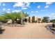 Gorgeous single-story home showcasing desert landscaping and mature trees under a partly cloudy sky at 27203 N 64Th Way, Scottsdale, AZ 85266