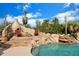 Stunning pool area with a charming fireplace, comfortable seating, and lush desert landscaping at 27203 N 64Th Way, Scottsdale, AZ 85266