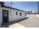 Minimalist backyard featuring a clean white exterior with ample gravel space and a secure black iron door at 346 W Edgemont Ave, Phoenix, AZ 85003