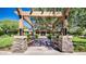 Inviting entrance framed by stone pillars and pergola, leading to a clubhouse with mature trees and manicured lawns at 4101 S Dewdrop Ct, Gilbert, AZ 85297