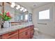 This bathroom features a wood vanity with granite counters, a framed mirror and walk in shower at 5349 W Acapulco Ln, Glendale, AZ 85306
