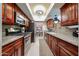 Galley kitchen with stainless steel appliances, granite countertops, and cherry wood cabinets at 5349 W Acapulco Ln, Glendale, AZ 85306