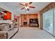 A brick fireplace is the focal point of this carpeted living room with a ceiling fan and sliding glass door at 5349 W Acapulco Ln, Glendale, AZ 85306