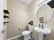 Powder room featuring pedestal sink, floating shelves, and decorative mirror offers a stylish and functional space at 6712 W Northview Ave, Glendale, AZ 85303