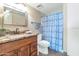 This bathroom boasts a wooden vanity with granite countertop and decorative blue shower curtain at 7960 E Camelback Rd # 409, Scottsdale, AZ 85251