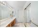 Bathroom featuring dual sinks, wood cabinets, a large mirror, and sliding mirrored door to the shower/toilet room at 8958 W Rosemonte Dr, Peoria, AZ 85382