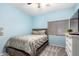 Cozy bedroom with a queen-sized bed, floral comforter, light blue walls, and neutral carpeting at 9569 W Redbird Rd, Peoria, AZ 85383