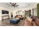 Comfortable living room featuring stylish decor, leather sofas, a large ceiling fan, and natural light from the window at 9569 W Redbird Rd, Peoria, AZ 85383