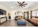 Cozy living room with dark brown leather sofas, wood-look flooring, and a large ceiling fan for added comfort at 9569 W Redbird Rd, Peoria, AZ 85383