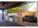 Outdoor kitchen with built-in grill, Traeger smoker and food preparation area under covered patio at 9569 W Redbird Rd, Peoria, AZ 85383