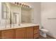Bright bathroom featuring a large mirror, wood cabinets, and a pristine white sink and toilet at 1213 W Beck Ln, Phoenix, AZ 85023