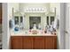 Bright bathroom with double sinks, a vanity with wood cabinets, and large mirrors reflecting the bedroom at 14428 W Moccasin Trl, Surprise, AZ 85374