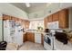 Functional kitchen with wood cabinets, white appliances, and a window overlooking the backyard at 14428 W Moccasin Trl, Surprise, AZ 85374