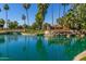 Scenic view of 'Sun Village' sign on a serene pond with lush greenery and mature palm trees at 14428 W Moccasin Trl, Surprise, AZ 85374