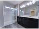 Well-lit Primary bathroom with dual sinks, dark cabinetry, a glass-enclosed shower, and tile floors at 16389 N 180Th Dr, Surprise, AZ 85388