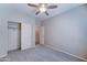 Another view of the cozy bedroom with neutral walls, plush carpet, ceiling fan, and closet with doors at 16389 N 180Th Dr, Surprise, AZ 85388