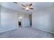 Spacious bedroom featuring plush carpet, ceiling fan, and an arched entrance to the ensuite bathroom at 16389 N 180Th Dr, Surprise, AZ 85388