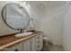 Bright bathroom features a modern oval sink, wood countertop, and a large round mirror at 16523 W Desert Bloom St, Goodyear, AZ 85338