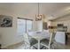 Bright dining area with stylish light fixture, tile floors, and view into the adjacent updated white kitchen at 16523 W Desert Bloom St, Goodyear, AZ 85338