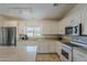 Bright kitchen with white cabinets, stainless steel appliances, and a large window over the sink at 16523 W Desert Bloom St, Goodyear, AZ 85338