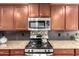 Close up on stainless steel oven and microwave appliances with dark wood cabinets and granite countertops at 2053 E Saddlebrook Ct, Gilbert, AZ 85298