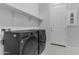 Well-lit laundry room features modern LG washer and dryer, white shelves, and a door to another room at 22788 E Orion Way, Queen Creek, AZ 85142
