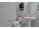 Bright half-bathroom with pedestal sink, toilet, and mirrored cabinet at 27667 W Mohawk Ln, Buckeye, AZ 85396