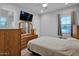 Cozy bedroom with wood dresser, TV, ceiling fan, and a bright window at 27667 W Mohawk Ln, Buckeye, AZ 85396